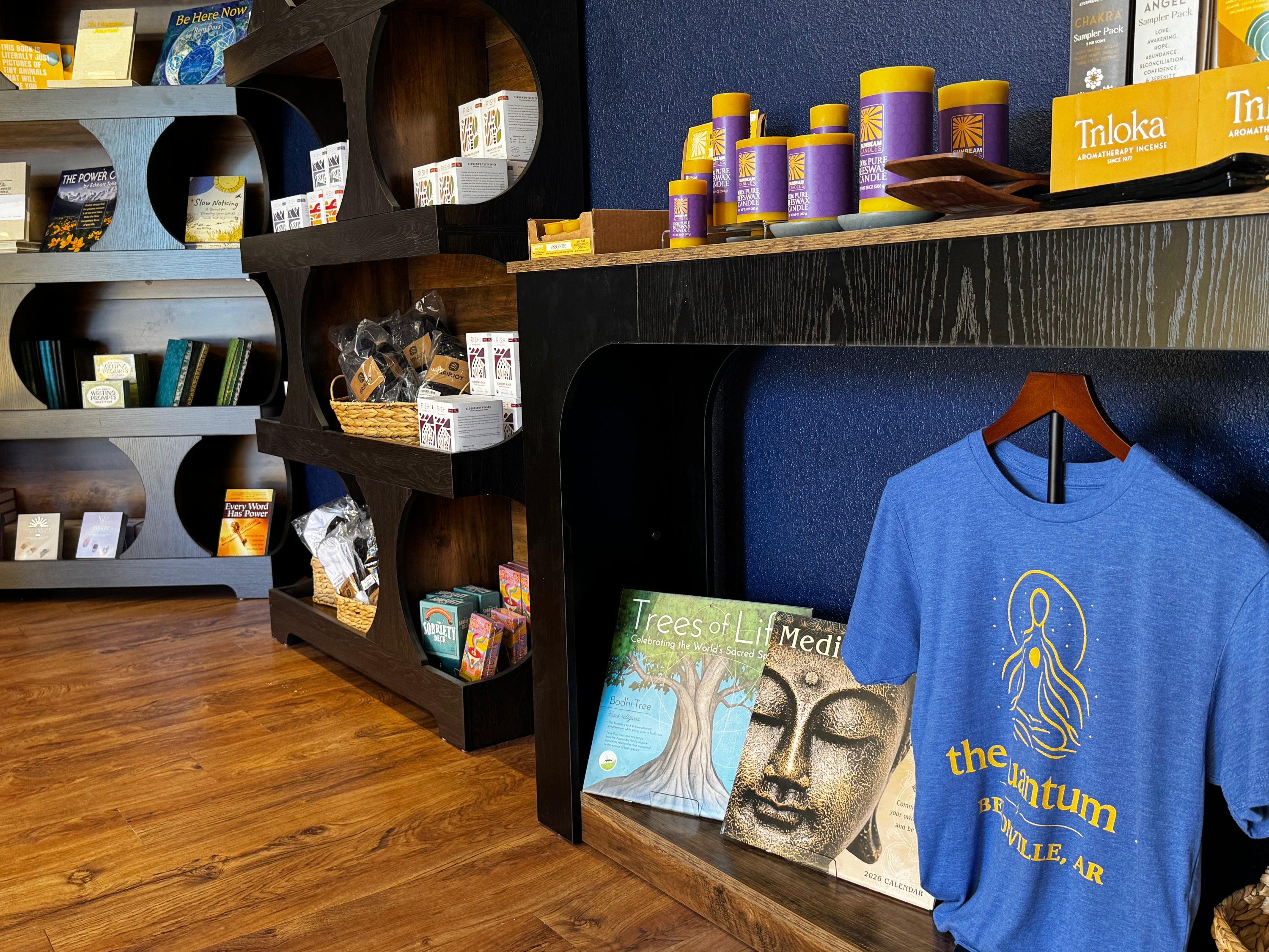 Store interior with books, products, and a blue t-shirt on a rack.