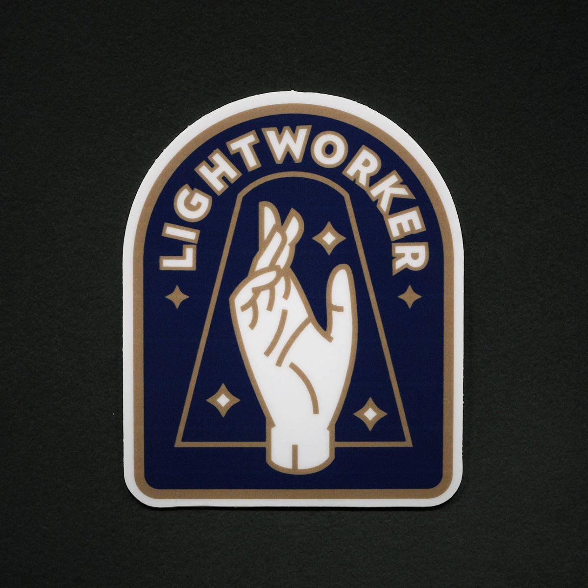 A die-cut sticker featuring a stylized white hand making a lightworker gesture on a dark blue background, with the word 'LIGHTWORKER' arched above in white and gold accents, shown on a dark textured background.