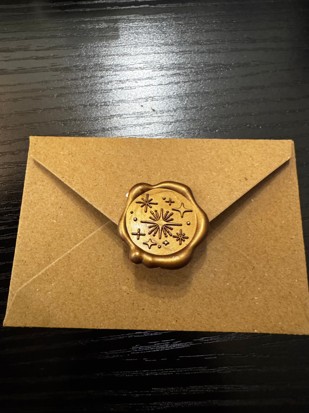 Brown gift card envelope with a gold wax seal on a dark surface